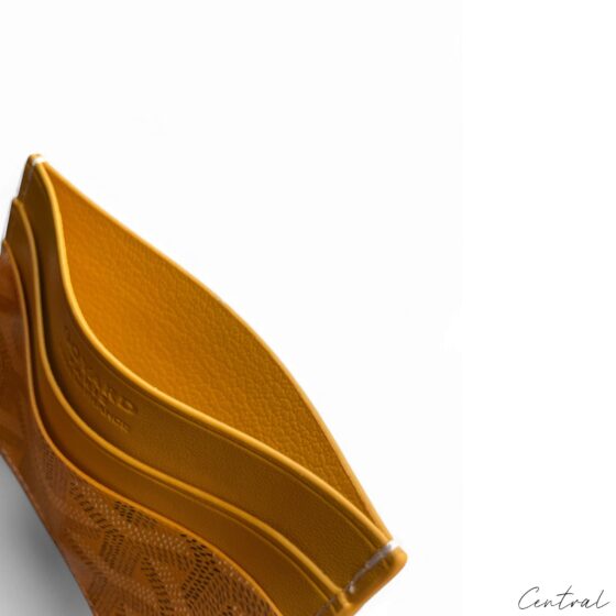 Yellow Goyard card holder from Central ae, featuring a sleek design and iconic logo pattern.