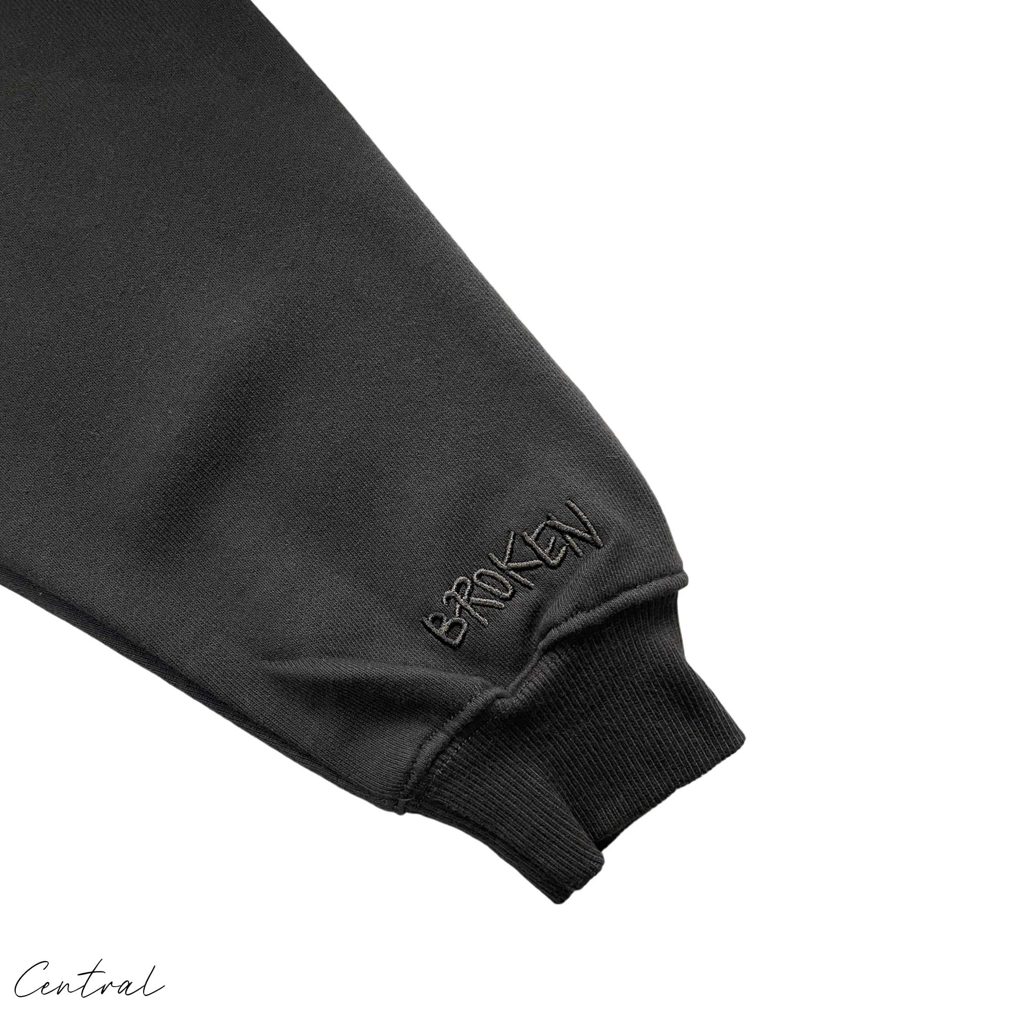 Central ae Broken Planet Out of the Shadows hoodie displayed on a hand, showcasing its design and fabric texture.