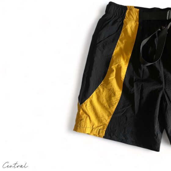 Black and yellow Corteiz Spring Shorts from Central ae displayed on a flat surface, showcasing fabric details and design.