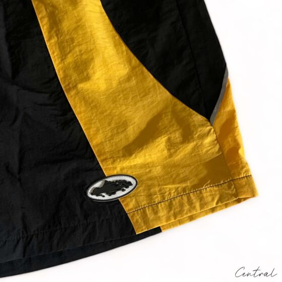 Black and yellow Corteiz shorts from Central ae, featuring a comfortable fit and stylish design, displayed on a flat surface.