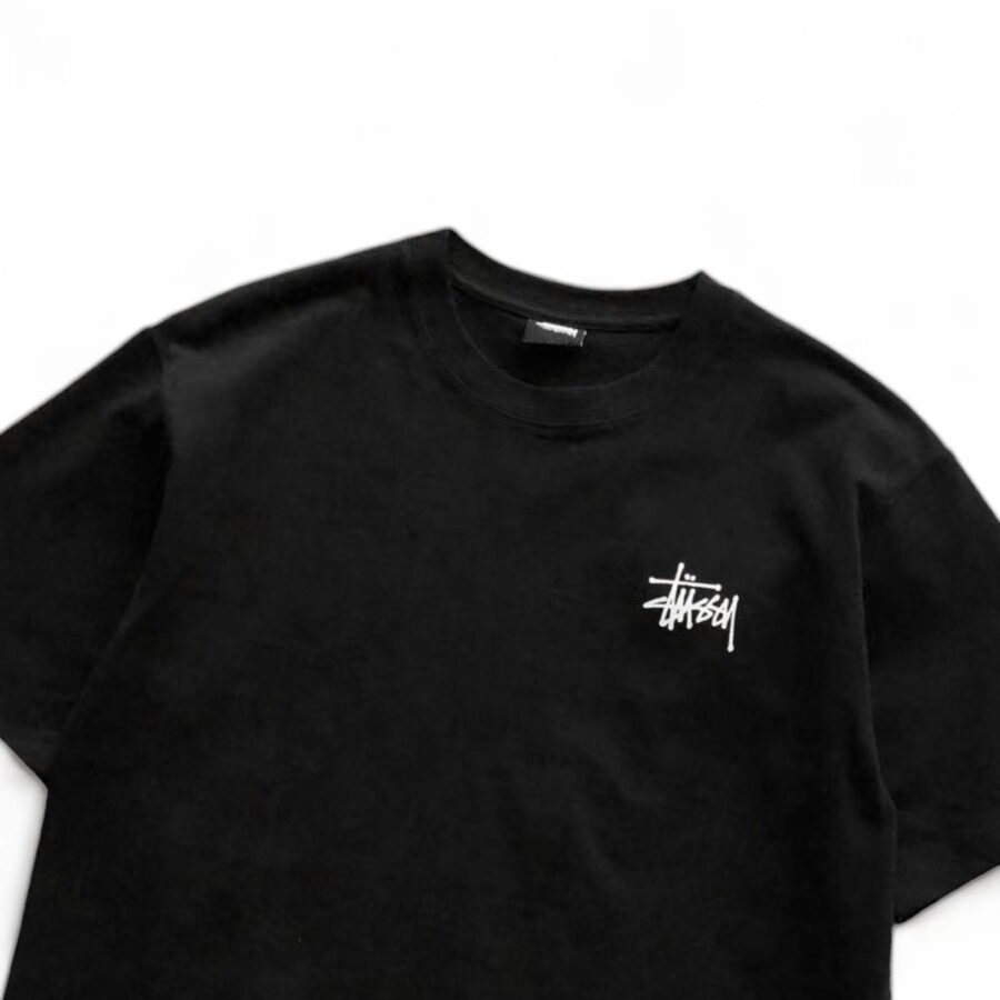 Black BASIC STÜSSY TEE featuring a classic crew neck and short sleeves, laid flat for a clear view of the fabric.