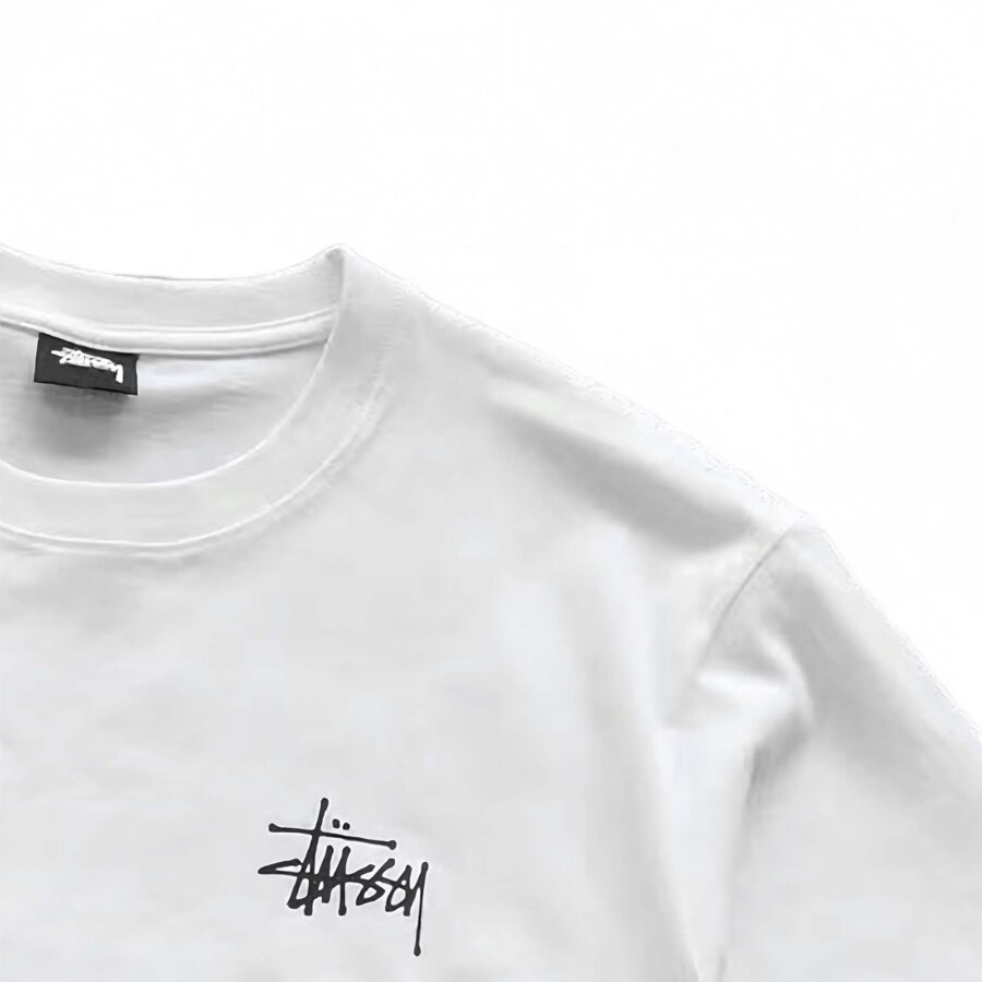 White BASIC STÜSSY TEE featuring a relaxed fit and logo detail, displayed on a plain background.