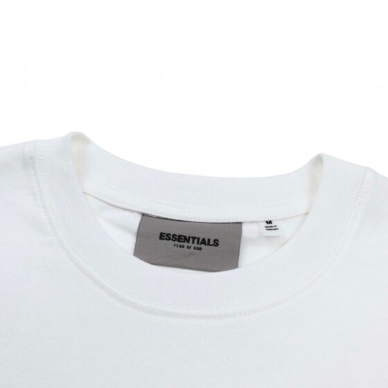 White oversized FOG ESSENTIALS T-shirt displayed on a flat surface, showcasing its relaxed fit and minimalist design.
