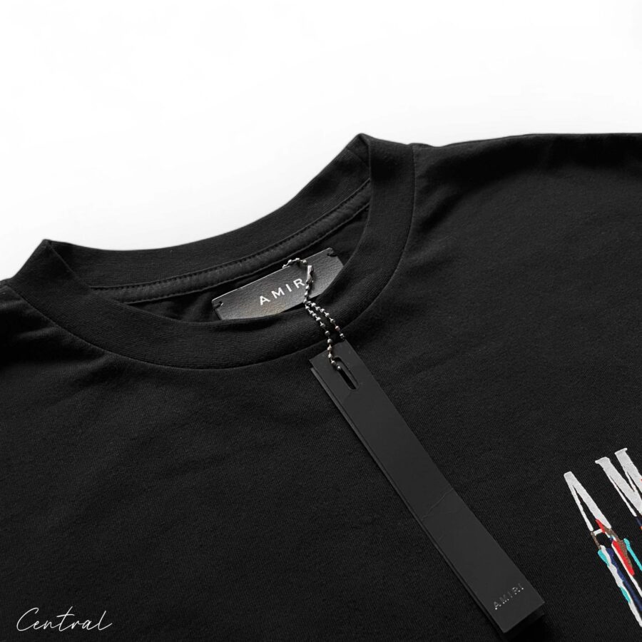 Amiri black t-shirt featuring a paint drip design, showcasing a casual streetwear style.