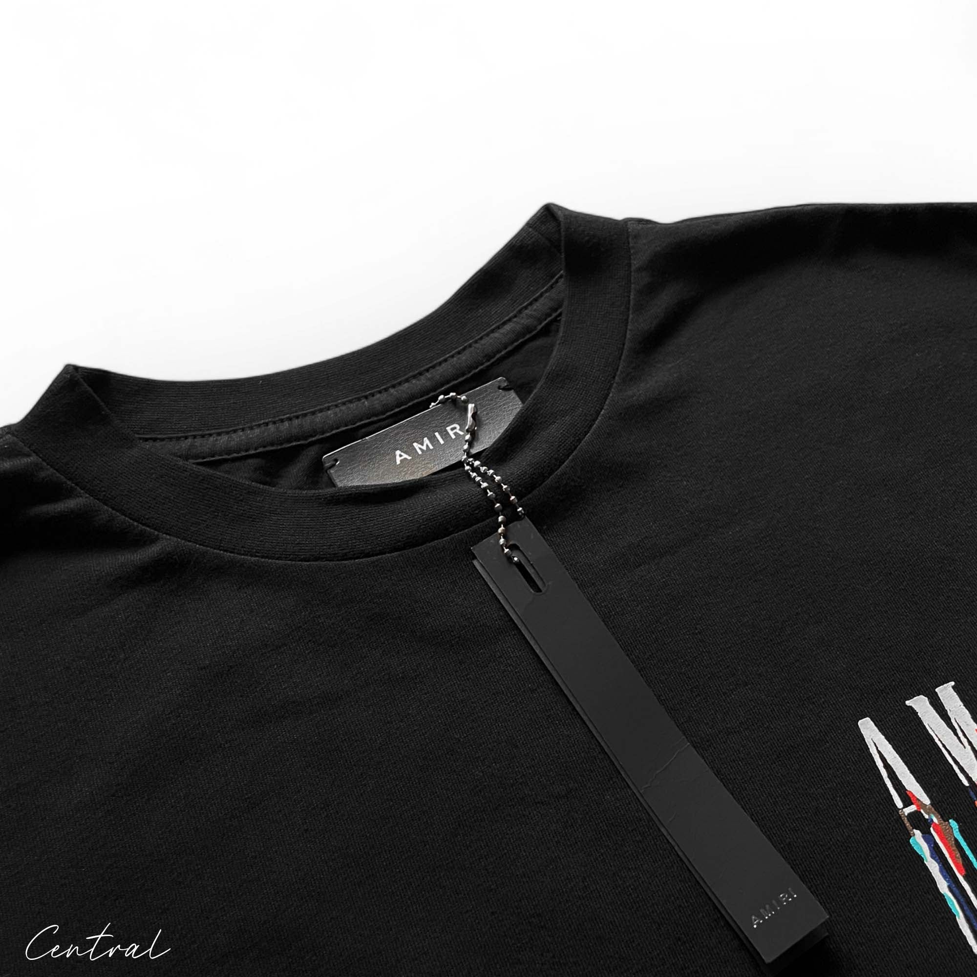 Amiri black t-shirt featuring a paint drip design, showcasing a casual streetwear style.
